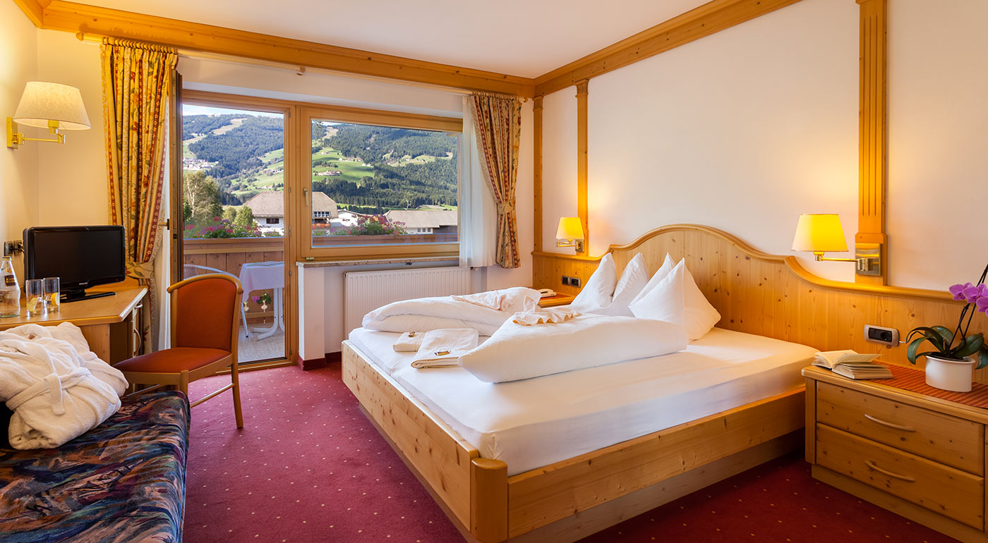 Doppelzimmer mit gemütlichem Bett und Blick auf den Balkon im Hotel Markushof